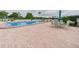 Community swimming pool surrounded by brick pavers and patio furniture at 700 Mirror Nw Ter # 702, Winter Haven, FL 33881