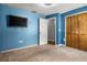 Empty bedroom with a mounted TV, double closet, carpet floor, and blue walls at 704 Butternut Pl, Lakeland, FL 33813