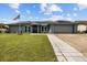 Charming single-story home featuring a lush lawn, solar panels, and an inviting walkway at 704 Butternut Pl, Lakeland, FL 33813