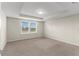 Bright bedroom featuring carpet, a ceiling tray, and a double window at 7247 Oakmoss Loop, Davenport, FL 33837