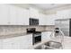 Modern kitchen featuring white cabinets, stainless steel appliances, and granite countertops at 7247 Oakmoss Loop, Davenport, FL 33837