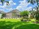 Backyard featuring lush green lawn, screen enclosed patio, and shade trees at 741 Canberra Rd, Winter Haven, FL 33884