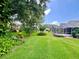 Expansive backyard with tropical landscaping, lush lawn, and a screened-in patio at 741 Canberra Rd, Winter Haven, FL 33884