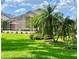 A spacious backyard with a screen enclosed patio, manicured lawn, and lush tropical landscaping at 741 Canberra Rd, Winter Haven, FL 33884