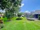 Spacious backyard featuring lush lawn, tropical trees, and a screened-in lanai at 741 Canberra Rd, Winter Haven, FL 33884