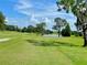 Beautiful golf course view showcasing lush green grass, a serene pond, and mature trees under a partly cloudy sky at 741 Canberra Rd, Winter Haven, FL 33884