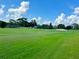 Expansive golf course view with lush green grass and trees under a bright blue sky with scattered clouds at 741 Canberra Rd, Winter Haven, FL 33884