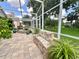 A covered patio with a brick floor, a stone bench, and a beautiful stone water feature at 741 Canberra Rd, Winter Haven, FL 33884