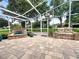 A screened-in patio boasts a stone water feature, potted plants, and a charming stone bench with cushions at 741 Canberra Rd, Winter Haven, FL 33884
