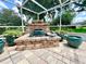 A stone waterfall feature with a sculpture and potted plants decorates this screened-in pool area at 741 Canberra Rd, Winter Haven, FL 33884