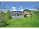 Backyard features a screened-in pool, lush lawn, and mature trees at 10708 Belo Horizonte Ave, Clermont, FL 34711