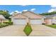 A view of two-car garages with mature landscaping and a neat strip of lawn at 13 Enclave Dr, Winter Haven, FL 33884