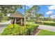 A view of the community guard house with lush shrubbery and mature trees at 13 Enclave Dr, Winter Haven, FL 33884