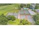 Overhead shot showcases the tennis courts and swimming pool surrounded by trees, grass, and a golf course at 13 Enclave Dr, Winter Haven, FL 33884
