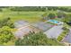 Aerial view featuring tennis courts and a community pool surrounded by green landscape and trees at 13 Enclave Dr, Winter Haven, FL 33884