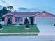 Charming single-story home featuring a well-manicured lawn, lovely landscaping, and a two-car garage at 1366 Merrimack Pl, Davenport, FL 33837