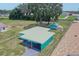 Aerial view of the turquoise home with a white roof, sheds, and a spacious yard at 2125 Hillcrest Rd, Auburndale, FL 33823