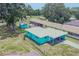 Aerial view of a turquoise home with a carport, sheds, and surrounding greenery at 2125 Hillcrest Rd, Auburndale, FL 33823
