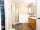 Bathroom with dual sinks, wooden cabinets, a glass enclosed shower, soaking tub and wood look floors at 2169 Rose Blvd, Winter Haven, FL 33881