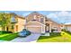 Tan two-story home featuring a two-car garage, a small yard, and a blue car in the driveway at 2169 Rose Blvd, Winter Haven, FL 33881
