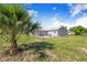 Spacious backyard with healthy green grass, and a view of the home's gray exterior at 2218 Melbourne Ave, Haines City, FL 33844