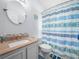Clean bathroom with updated vanity, decorative mirror, and shower with blue patterned curtain at 2538 Crown Ridge Cir, Kissimmee, FL 34744