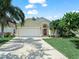 Charming single-story home with a well-maintained lawn, palm trees, and a two-car garage at 2538 Crown Ridge Cir, Kissimmee, FL 34744