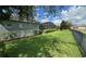 Expansive backyard featuring a screened-in lanai, lush lawn, privacy fence, and well-manicured hedges at 25863 Crossings Bluff Ln, Sorrento, FL 32776