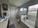 Bright bathroom featuring a soaking tub, glass shower, and neutral tile at 25863 Crossings Bluff Ln, Sorrento, FL 32776