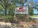 Stone community sign with a red feather logo amongst mature landscaping at Red Tail community entrance at 25863 Crossings Bluff Ln, Sorrento, FL 32776