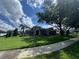 Charming single-story home with lush green lawn, mature tree, and professionally landscaped flower beds at 25863 Crossings Bluff Ln, Sorrento, FL 32776