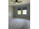 Bright bedroom with plush carpeting, neutral paint, and two sunny windows at 2609 Village Lakes Blvd, Lakeland, FL 33805