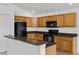 Bright kitchen with wood cabinets, black appliances, and tile flooring offers a functional and stylish cooking space at 2740 Rochelle Dr, Winter Haven, FL 33881
