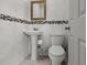 Charming bathroom featuring mosaic tile accent, pedestal sink, toilet and decorative mirror at 2800 Sunset Nw Dr, Winter Haven, FL 33881