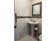 Cozy half-bathroom with pedestal sink, decorative tile border, and a framed mirror at 2800 Sunset Nw Dr, Winter Haven, FL 33881