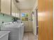 Functional laundry room with washer, dryer, utility sink, upper cabinets and a small window at 2800 Sunset Nw Dr, Winter Haven, FL 33881
