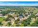 An aerial shot showcases a community with a pond, surrounded by lush trees and green fields under a clear sky at 2861 Pond View Dr, Haines City, FL 33844