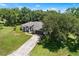 Aerial shot shows a well-maintained home, lush lawn, and a driveway leading to the garage, all surrounded by trees at 2861 Pond View Dr, Haines City, FL 33844