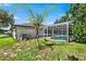 Backyard view of a screen-enclosed pool with an adjacent patio, surrounded by lush greenery and partial views of the house at 2861 Pond View Dr, Haines City, FL 33844