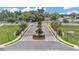 Gated community entrance featuring decorative landscaping, a brick-paved roundabout, and tree-lined streets at 308 Kissengen Park Dr, Bartow, FL 33830