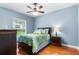 Serene blue bedroom with a patterned bedspread, hardwood floors, and a large window at 328 Hamilton Shores Ne Dr, Winter Haven, FL 33881