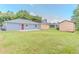 A large backyard with two sheds, a gray home, a red door, and a spacious lawn at 411 Red Hawk Loop, Winter Haven, FL 33880