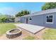 A backyard with a gray home, a red door, a wooden deck and a stone firepit for outdoor enjoyment at 411 Red Hawk Loop, Winter Haven, FL 33880