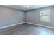 Empty bedroom has wood-look floors, soft gray walls, a ceiling fan, and a window at 411 Red Hawk Loop, Winter Haven, FL 33880