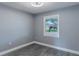 Empty bedroom features a view outside, wood-look floors, soft gray walls, and a ceiling fan at 411 Red Hawk Loop, Winter Haven, FL 33880