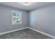 Empty bedroom features a view outside, wood-look floors, soft gray walls, and a ceiling fan at 411 Red Hawk Loop, Winter Haven, FL 33880