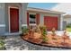 Close up of home's front door and red garage, surrounded by mature landscaping at 411 Red Hawk Loop, Winter Haven, FL 33880