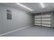 Spacious two car garage has gray walls, painted floor, and overhead lights at 411 Red Hawk Loop, Winter Haven, FL 33880