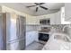 Updated kitchen with white cabinets, stainless steel appliances, granite countertops, and wood-look floors at 411 Red Hawk Loop, Winter Haven, FL 33880