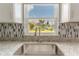 Close-up of a kitchen sink with granite countertops, stylish faucet, and view of the backyard through a window at 411 Red Hawk Loop, Winter Haven, FL 33880